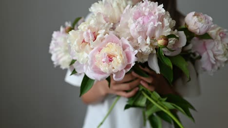 anonymous girl child standing with blooming peony flower with stem