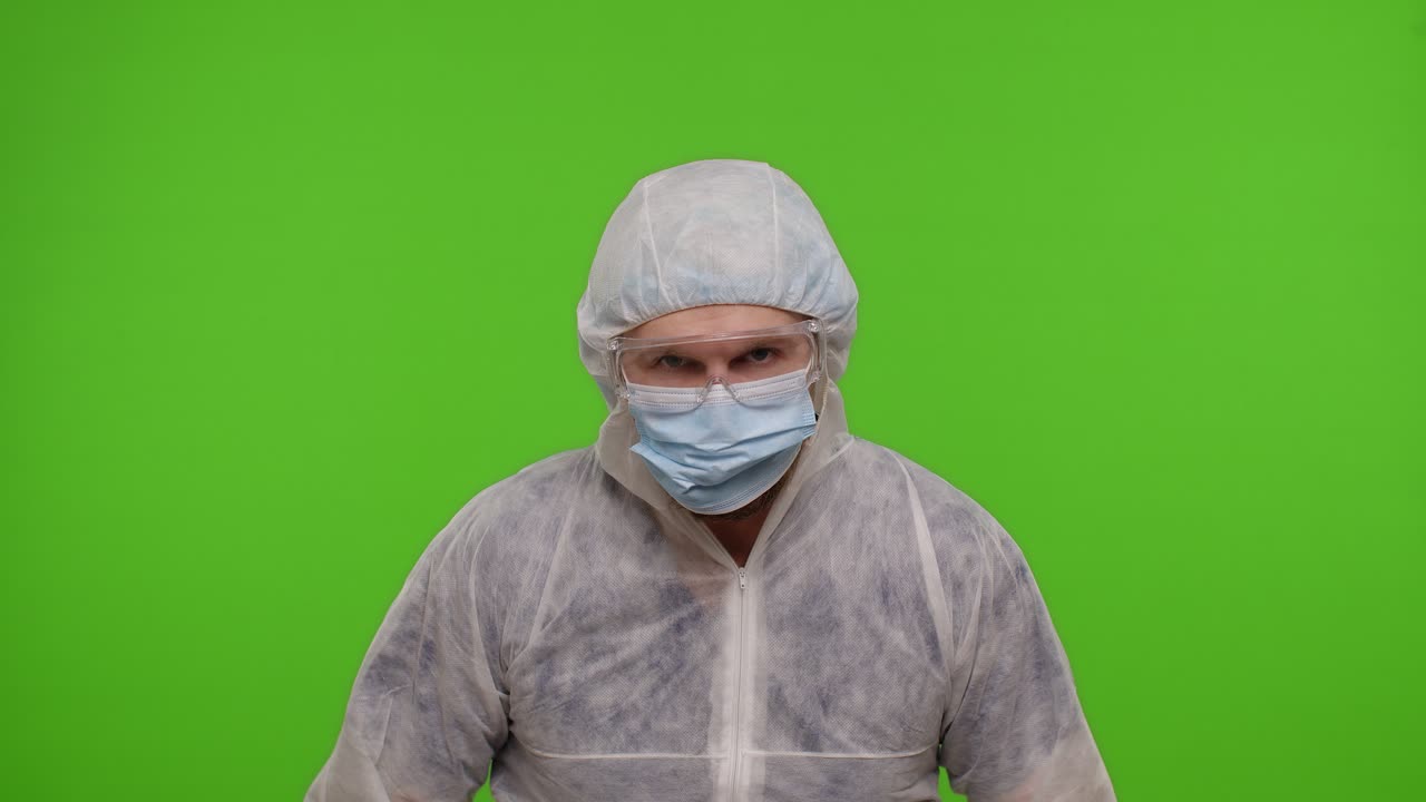 두 개의 주사기를 가진 ppe 보호복을 입은 미치광이 의사는 춤추고, 어리석고, 청한 얼굴을 하고 있습니다.