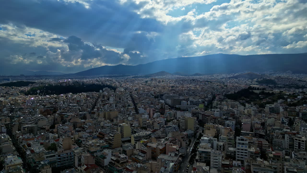 rayos de sol brillando a través de las nubes hasta la antigua ciudad de atenas, grecia, drone