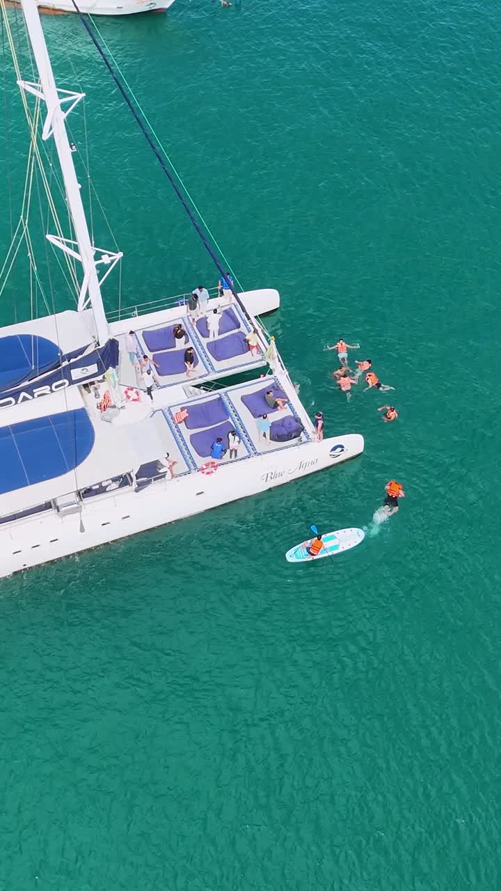 vista aérea de un catamarán con personas nadando cerca en el mar turquesa de phuket, tailandia, bajo la luz del día brillante