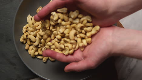 overhead shot of hands reaching into bowl of cashew nuts shot in slow motion