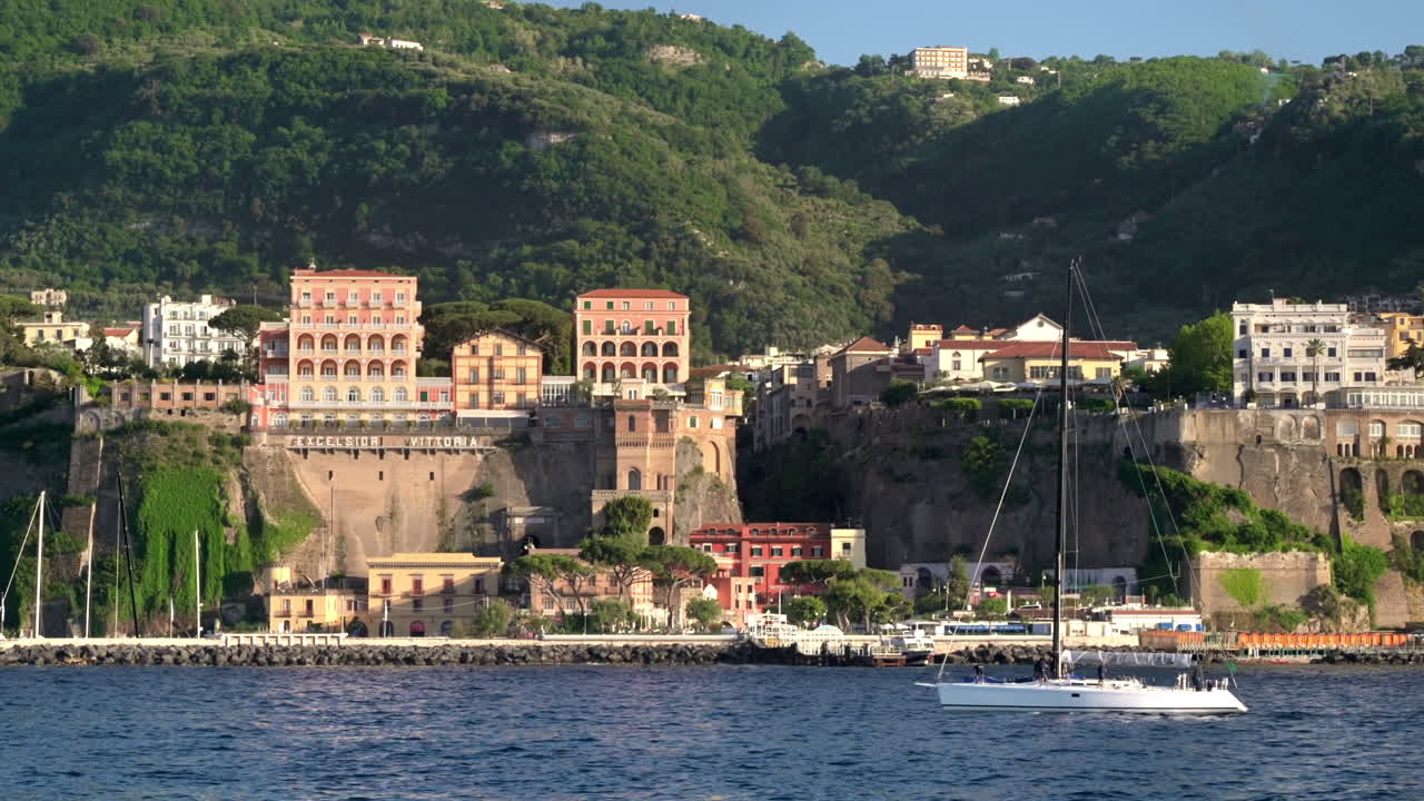 Vista della costa del Mar Tirreno a Sorrento, Italia. File di edifici, spiaggia, scogliere, yacht in movimento, vegetazione. Vista da una barca