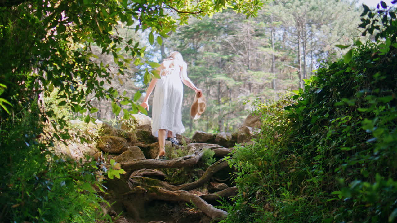 Adventurous girl climbing forest trail spending summer nature weekend back view