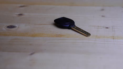 black-key-with-a-curved-key-bit-lies-on-a-light-tabletop-and-rotates