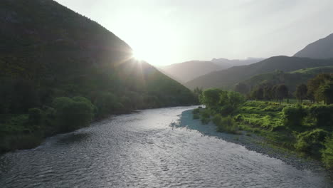 drone flying low over the motueka river as the sun starts to set over the hills, in new zealand