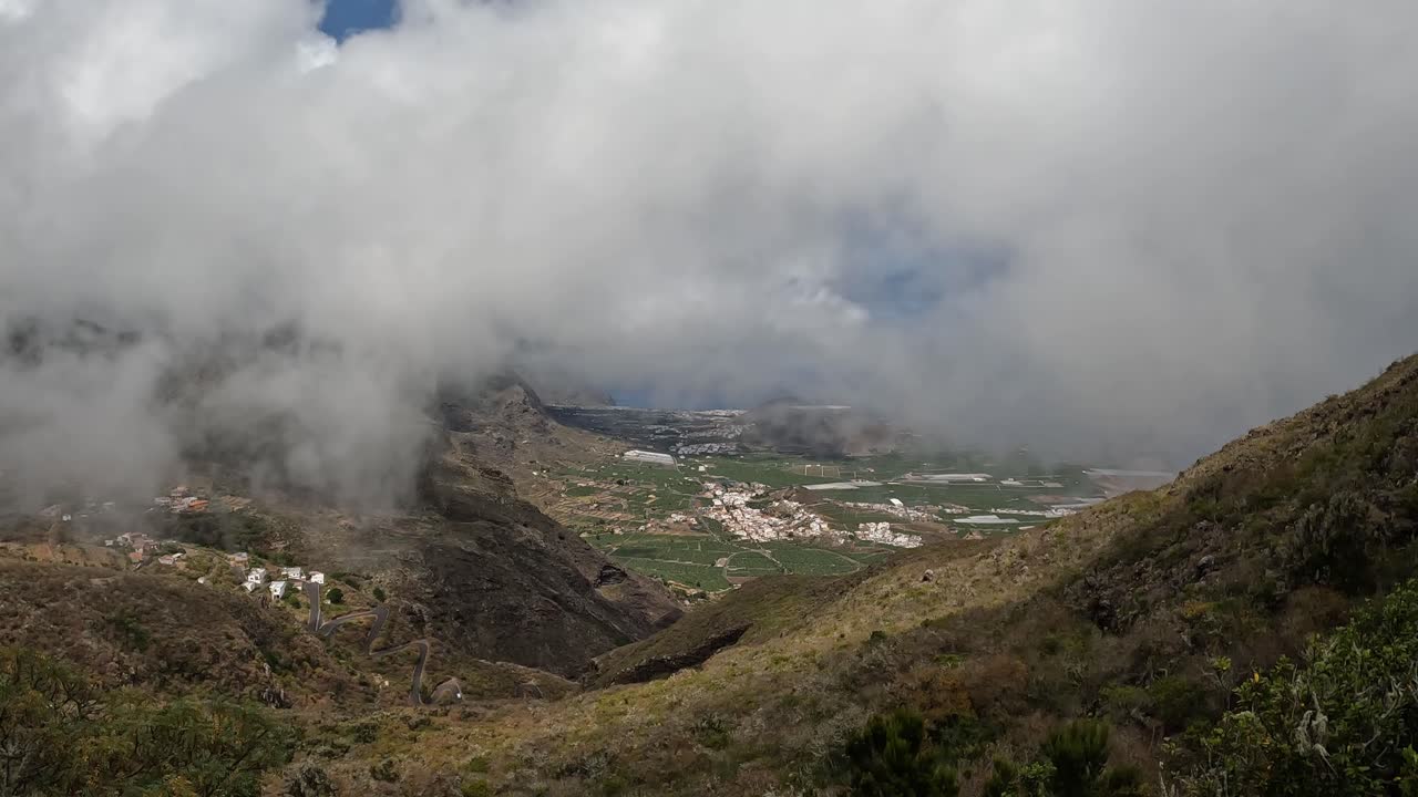 nubes rodando por encima de las colinas empinadas y carreteras ventosas en la costa norte de tenerife, islas canarias- disparo de trípode