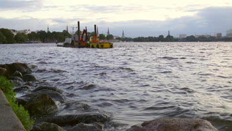 dredger on a lake with city skyline in the background