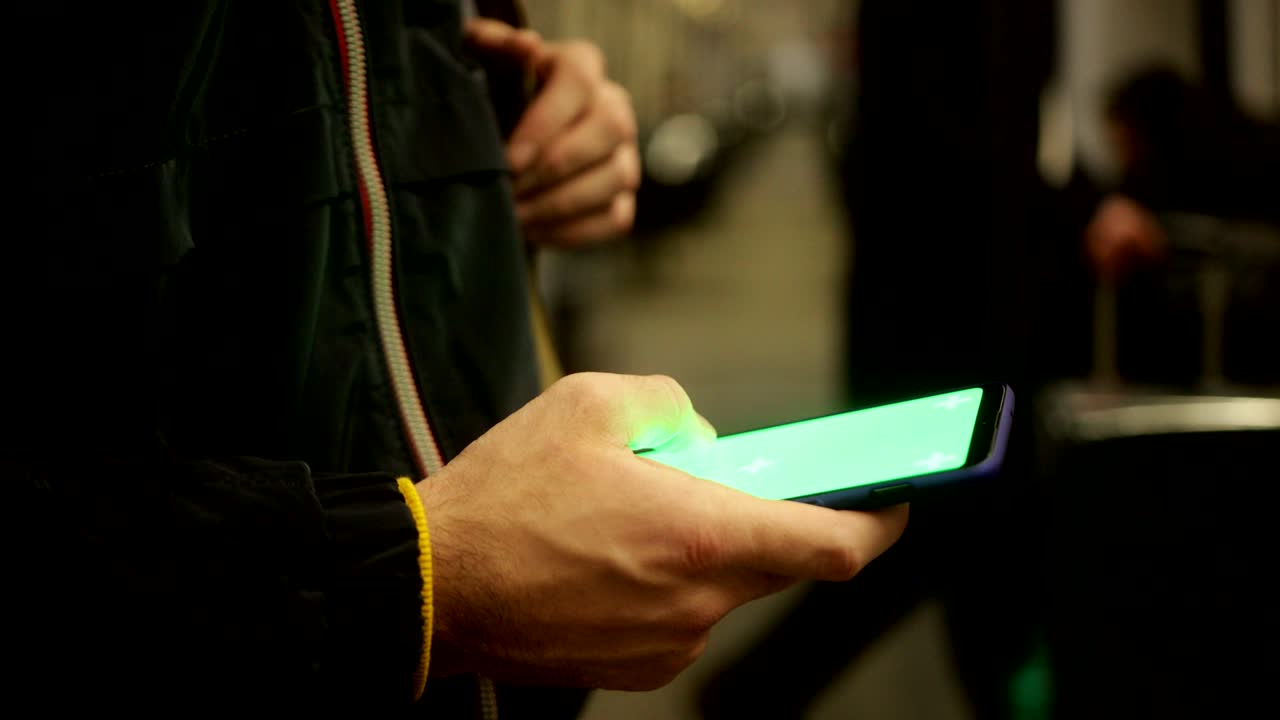 hombre de cerca usando un teléfono inteligente con pantalla verde en el tren
