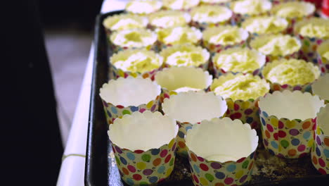 filling cute paper cups with batter, using an ice cream spoon