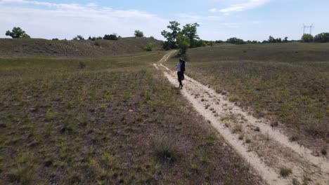 man portraying poet sandor petofi walks dirt road, bends down to examine something