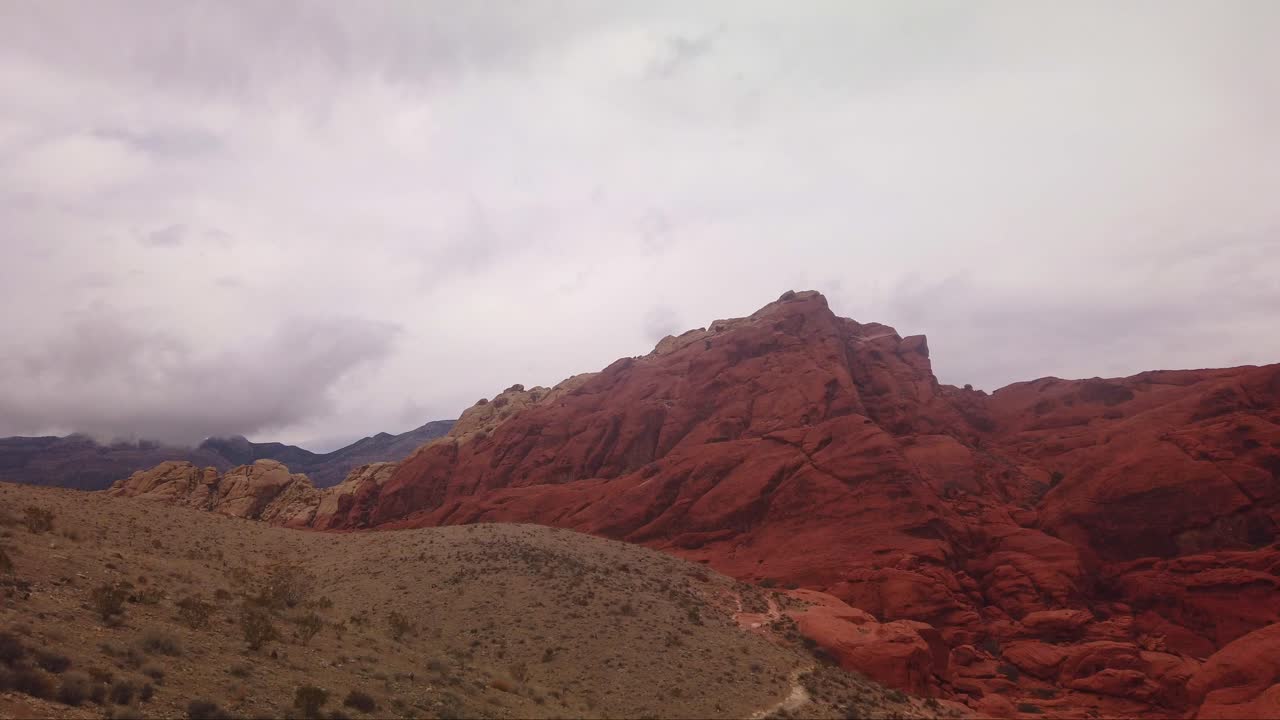 toma estática de cardán de nubes gruesas que se mueven sobre formaciones de roca roja brillante en el cañón de roca roja, nevada