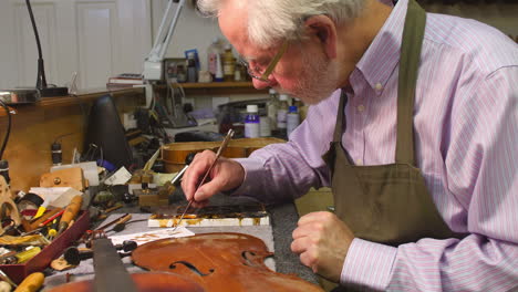 man restoring violin in workshop