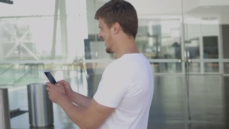 un joven animado mirando su teléfono inteligente.