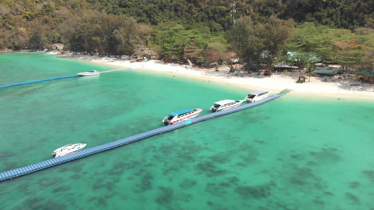 바나나 해변, 코 헤이, 태국의 에메랄드 물 위에 정박 된 관광 관광 보트로 붐비는 떠 다니는 플랫폼 부두 - 공중 비행 하강 샷
