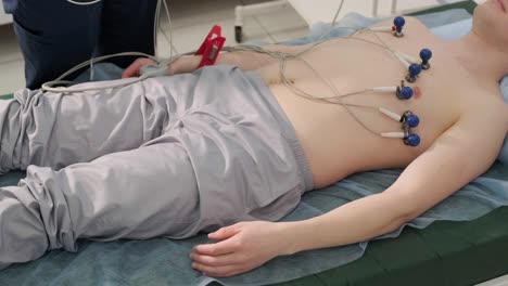 cardiac examination in a hospital with a professional cardiograph. the patient lies on a bed with connected sensors.