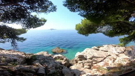 hermosa, calurosa y soleada vista del día sobre el mar desde las copas de los pinos a la sombra con la costa rocosa debajo de sus pies