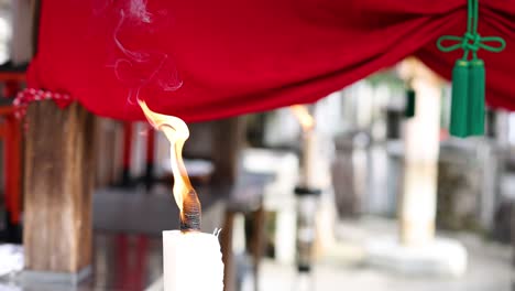 candle flame flickers and smokes against red backdrop