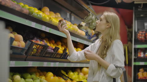 young woman choosing ripe mangoes in grocery store. vegan zero waste girl buying fruits and veggies in organic supermarket and using reusable produce bag. 4k slowmotion