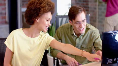 happy diverse female and male creative colleagues in casual discussion at computer, slow motion