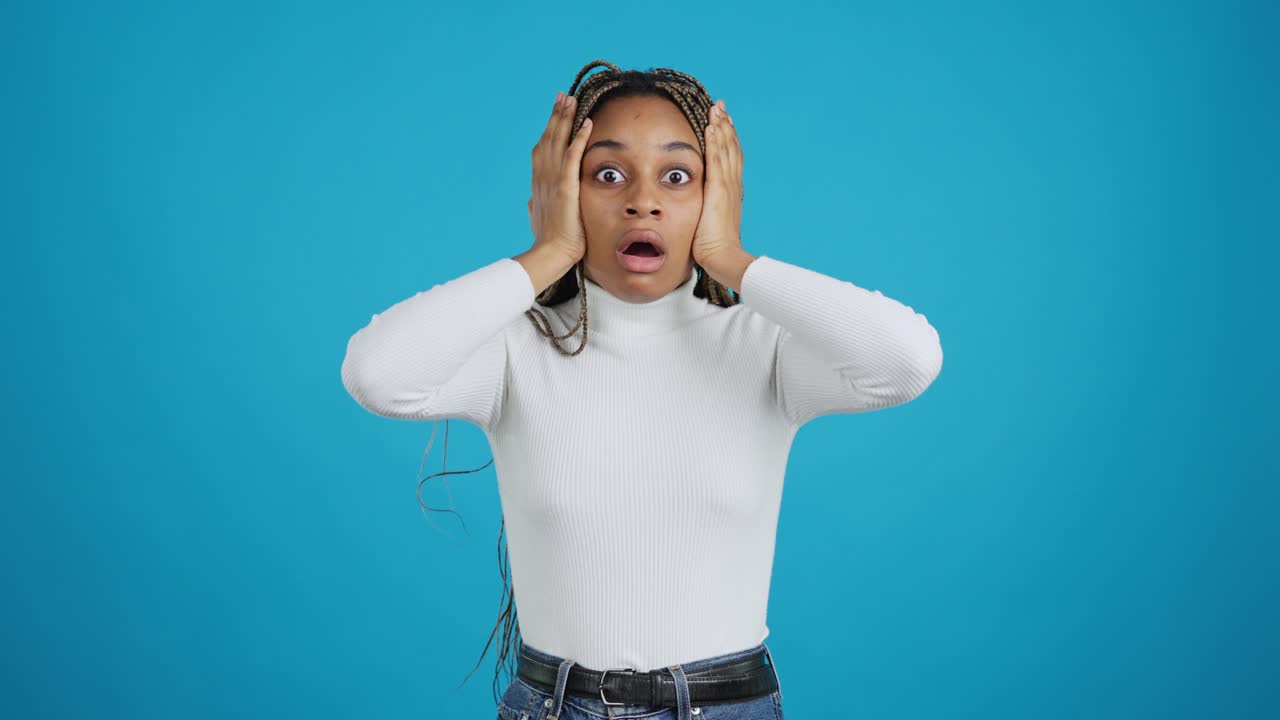 Shocked Woman with Hands on Face Against Blue Background