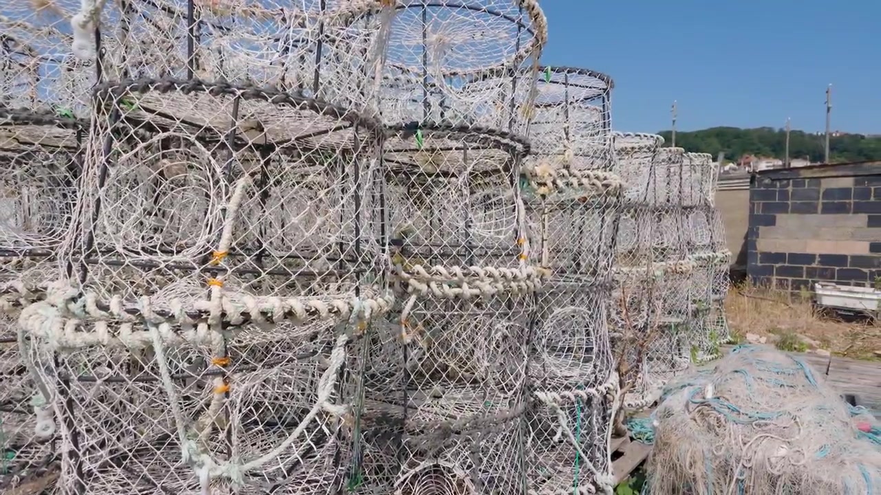 영국 헤이스팅스 해변에 쌓여 있는 가재와 랍스터 통발. 엮인 철망을 가로지르는 느린 오른쪽 팬 촬영.