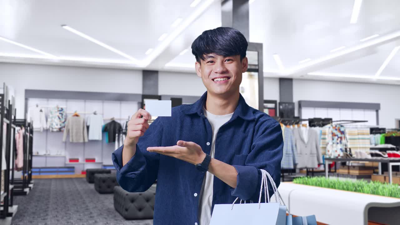 幸せな顧客が衣類店でカードとショッピングバッグを保持している