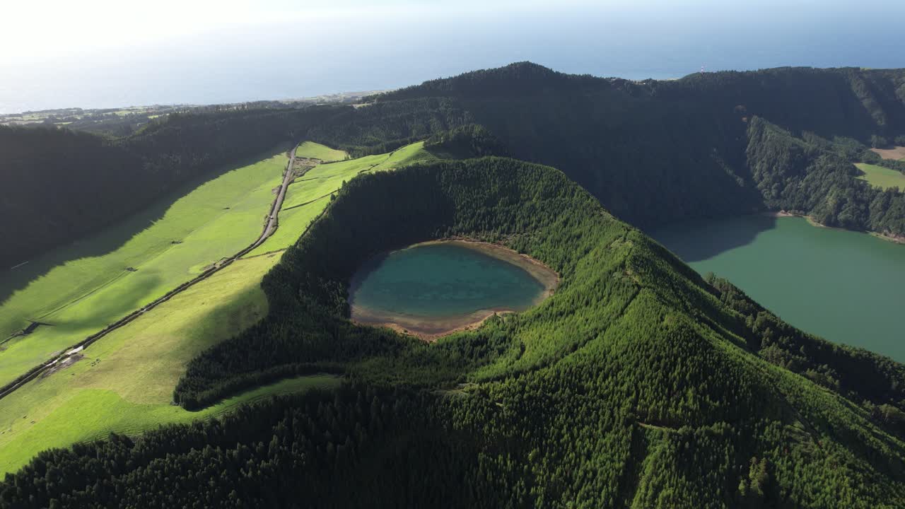 View over Lagoa Rasa with forested crater and Lagoa Verde in the distance in Sete Cidades on Sao Miguel island in the Azores as the drone moves right