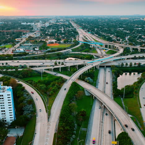 splendid view of miami district with large road interchange. multiple cars run by the highways and freeways in green area of the city. aerial perspective.