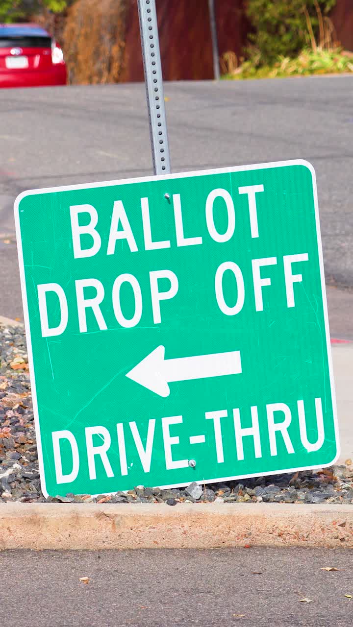 Vertical video of a ballot drop-off sign with a large arrow stands at the roadside, highlighting democratic participation, civic responsibility, election safety, secure voting, importance of freedom