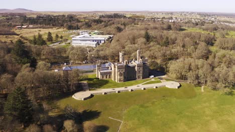 drone tilt-shot of stornoway, revealing the lews castle, uhi outer hebrides, and the landscape beyond it on a sunny day on the isle of lewis, outer hebrides of scotland, united kingdom