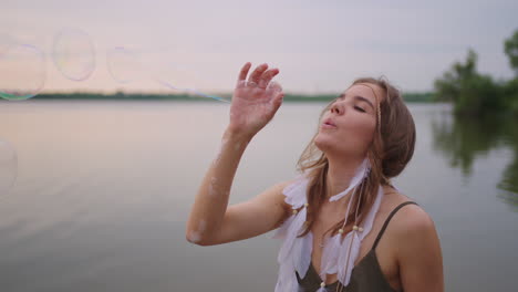 a young girl artist shows magic tricks using soap bubbles. create soap bubbles in your hands and inflate them location theatrical circus show at sunset