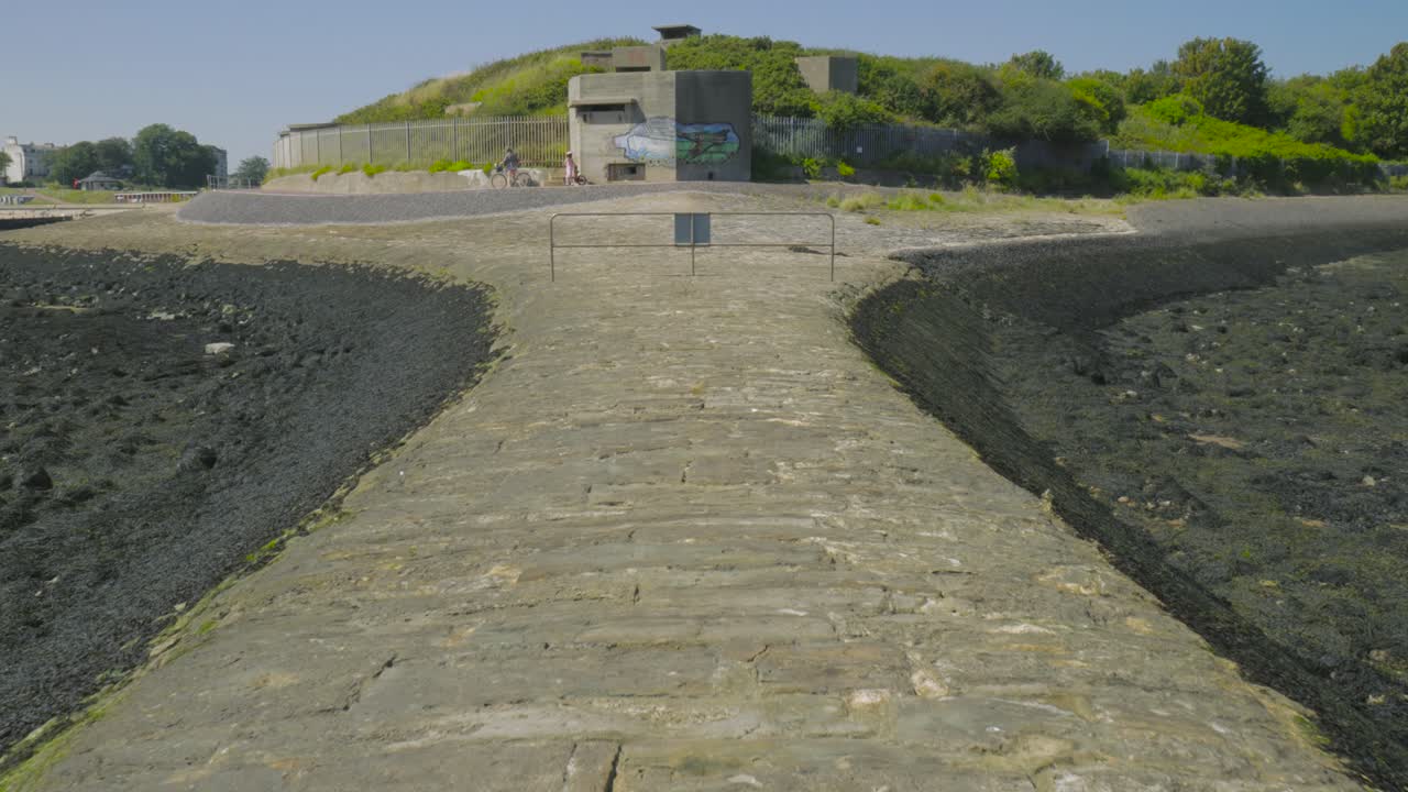 dolly en el rompeolas de adoquines con el bunker de dunas en el fondo