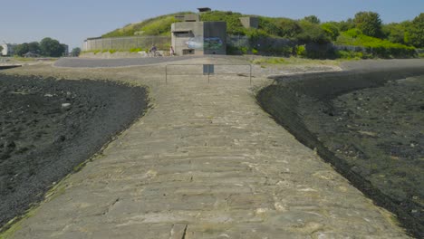 dolly in on cobblestone breakwater with dune bunker in background