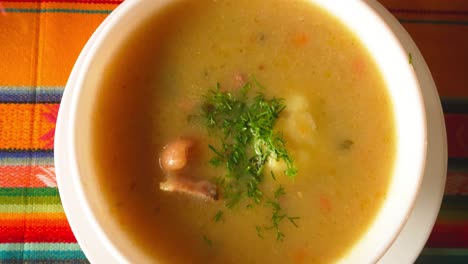 overhead shot of a traditional soup with herbs on a vibrant andean tablecloth. ideal for culinary, culture, or tourism content.
