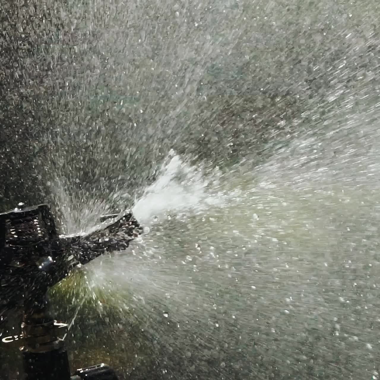 drops of water are watering plants in the yard. Automatic watering system of plants. Aerosol irrigation of garden. Slow motion