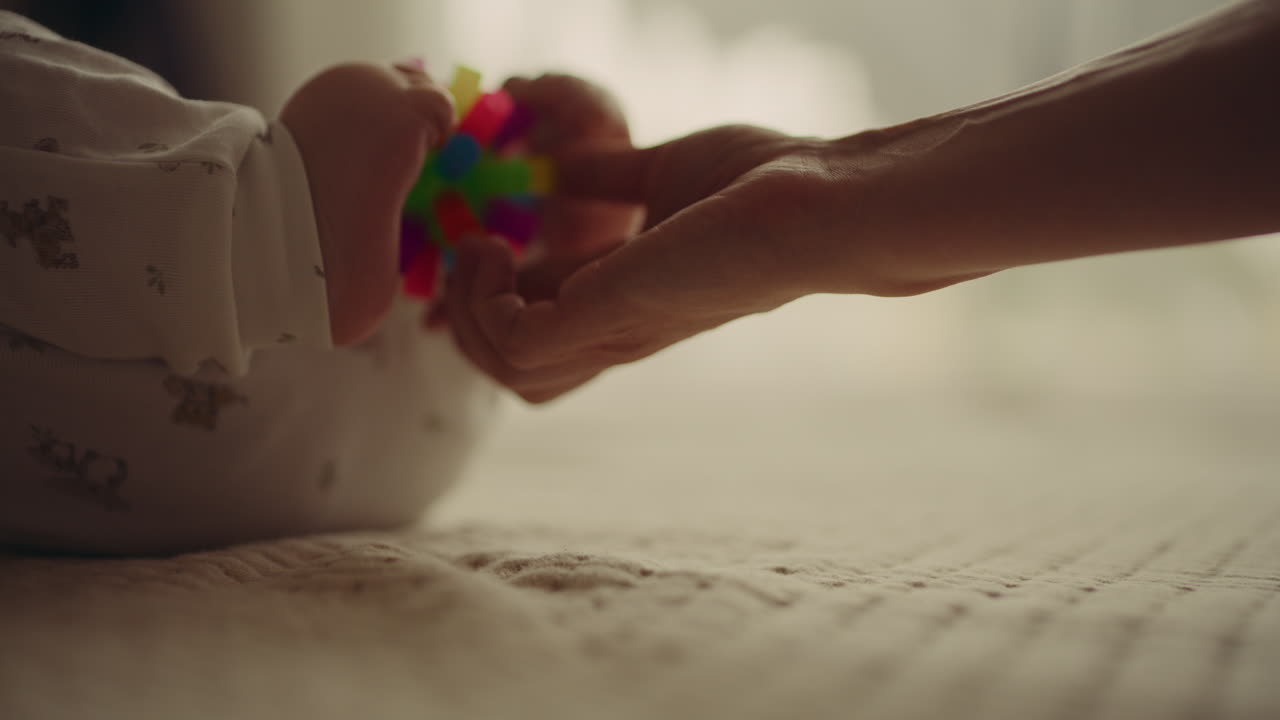Baby playing with a toy with mother's hand