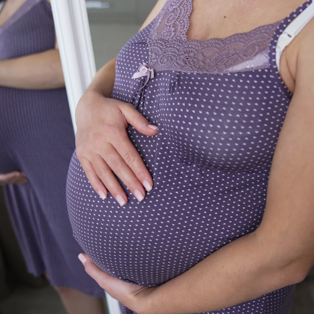 Donna incinta in attesa di un bambino sta in piedi vicino allo specchio. Le mani della donna le toccano la pancia, in attesa del suo bambino. Un gatto nero salta nel riflesso dello specchio.