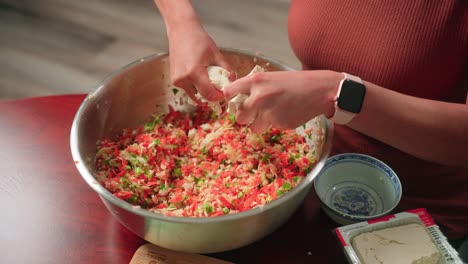 añadiendo tofu al relleno de verduras en un cuenco grande