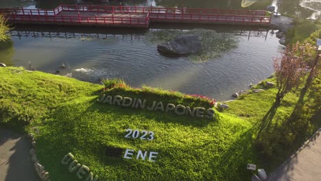 aerial orbit shot of jardin japones garden park 2023 during golden sunset with lake