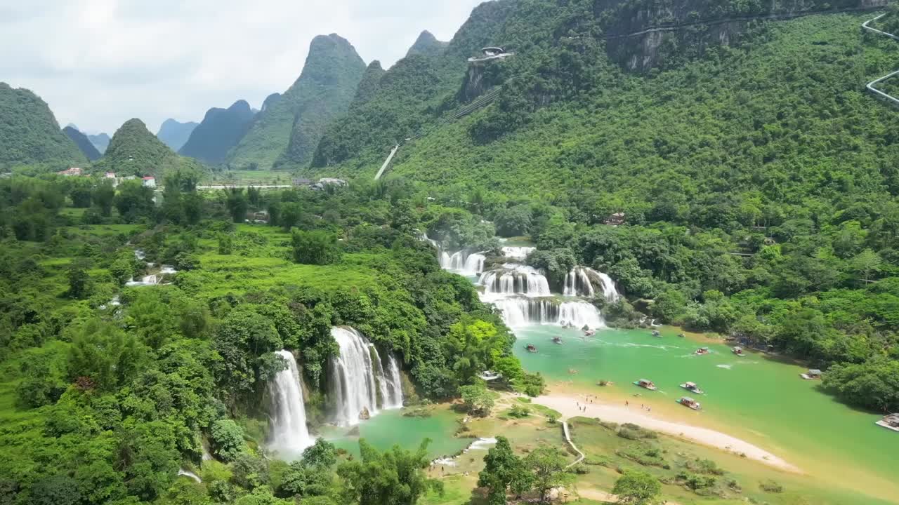 Ban Gioc Waterfalls cascade down multiple tiers into a turquoise river surrounded by lush greenery and karst mountains, creating one of Vietnam’s most stunning natural scenes.
