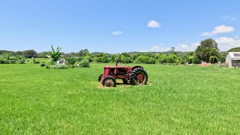 red tractor driving through a sunny, grassy landscape