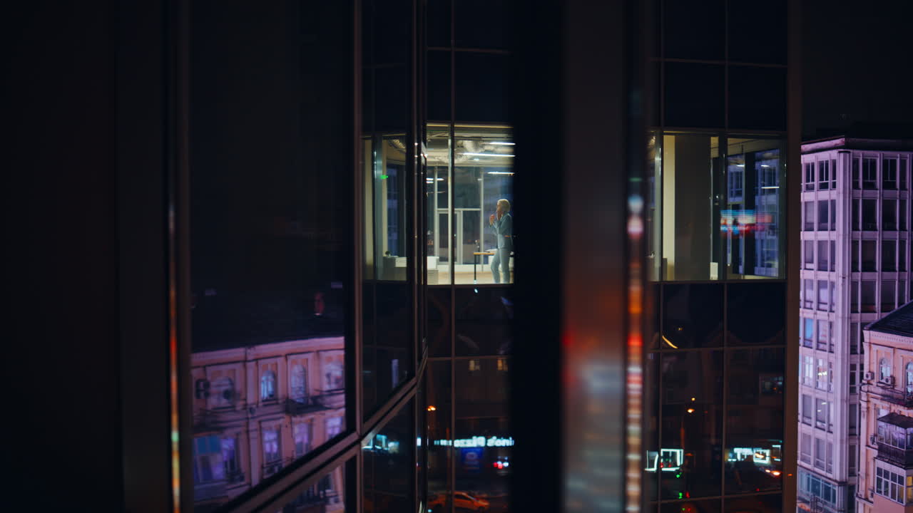 Silhouette di donna d'affari che telefona vicino alla finestra di notte. Direttore che parla di lavoro al telefono