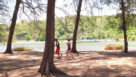 people running along the shore of a lake in a park