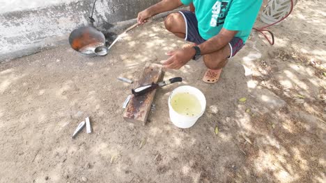 Man-molding-fishing-weights-outdoors-in-daylight,-using-lead-and-a-handheld-mold