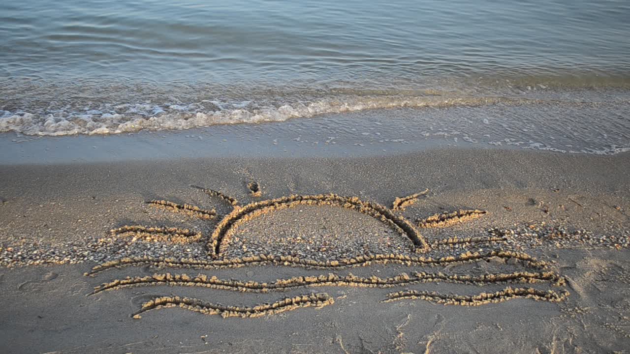 Drawing on sand. Drawing of waves and hot summer sun on golden beach sand conceptual of a summer vacation on a tropical beach