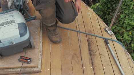 carpenter removing old caulking from boat foredeck