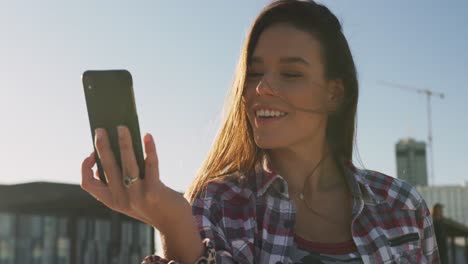 retrato de una mujer caucásica sonriente tomando una selfie en un skatepark