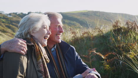 loving active senior couple hugging as they sit and look at countryside together