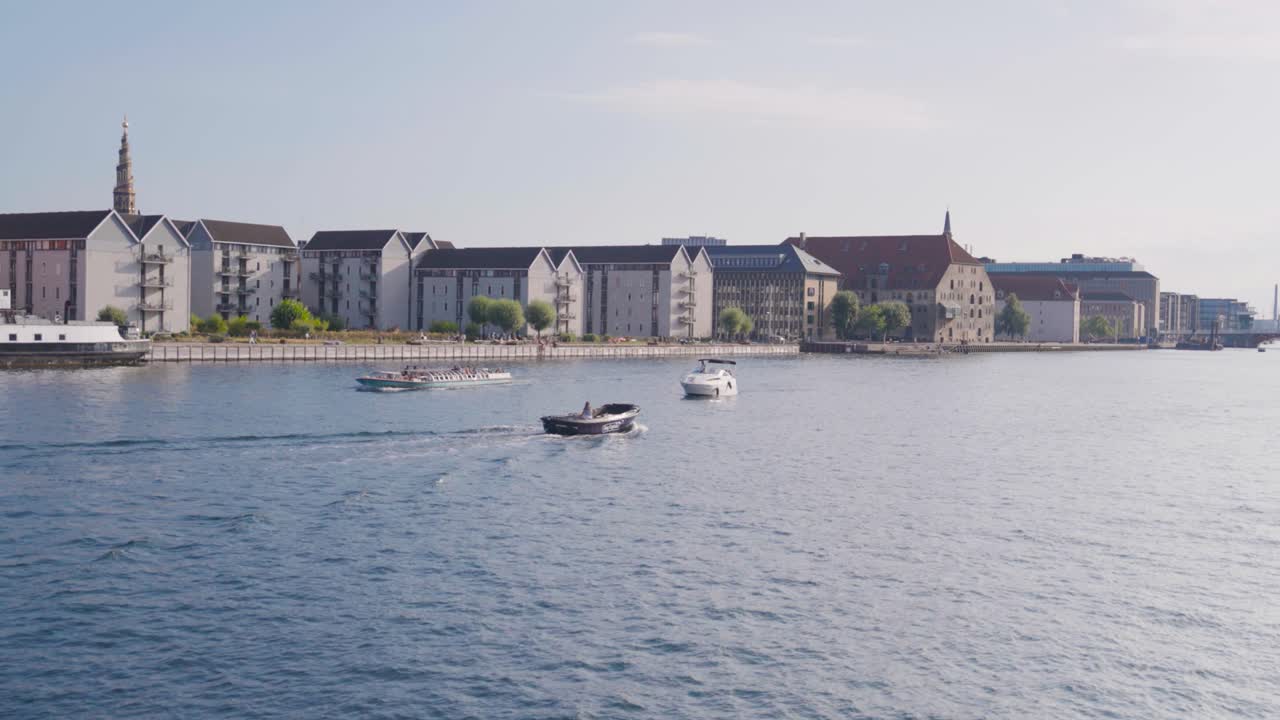 Naturskøn udsigt over både i en kanal i København med et byggeprojekt ved vandet.