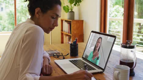 Afroamerikanische-Frau-Macht-Sich-Notizen,-Während-Sie-Zu-Hause-Einen-Videoanruf-Auf-Dem-Laptop-Führt